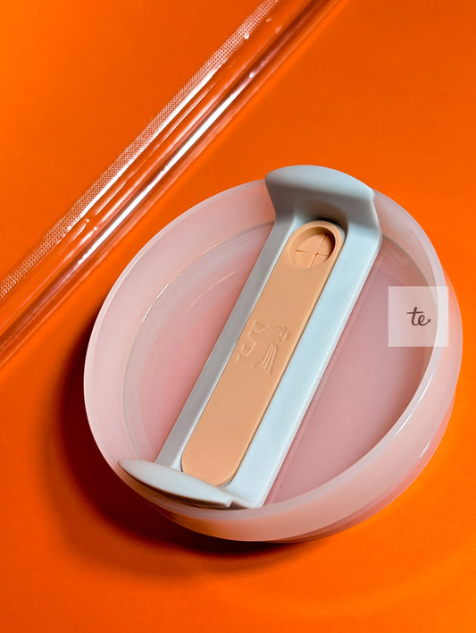 Close-up of a silicone collapsible container lid with a gray and beige locking mechanism on an orange background