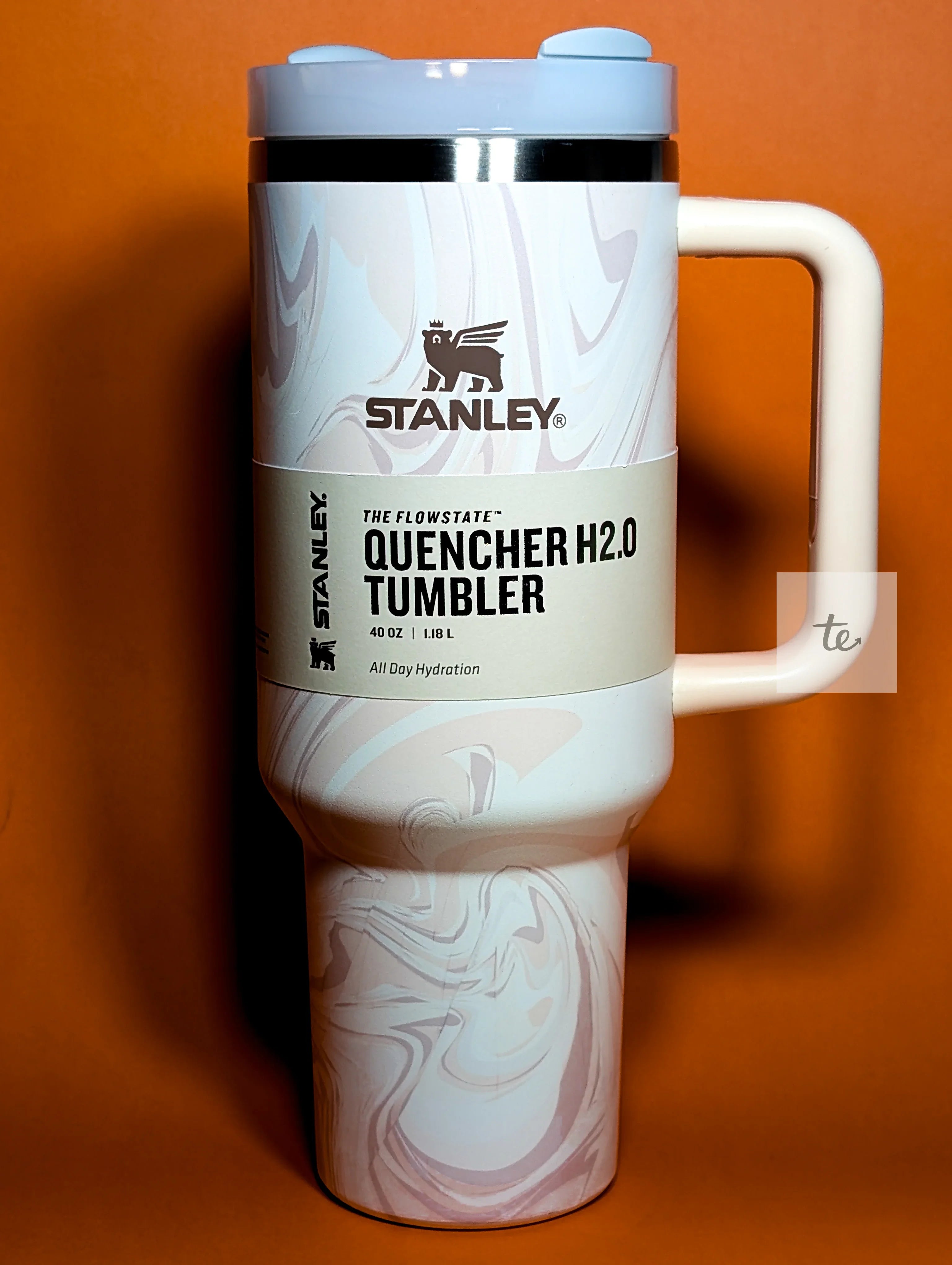 Stanley Quencher H2.0 40oz marble-patterned insulated tumbler with handle on orange background