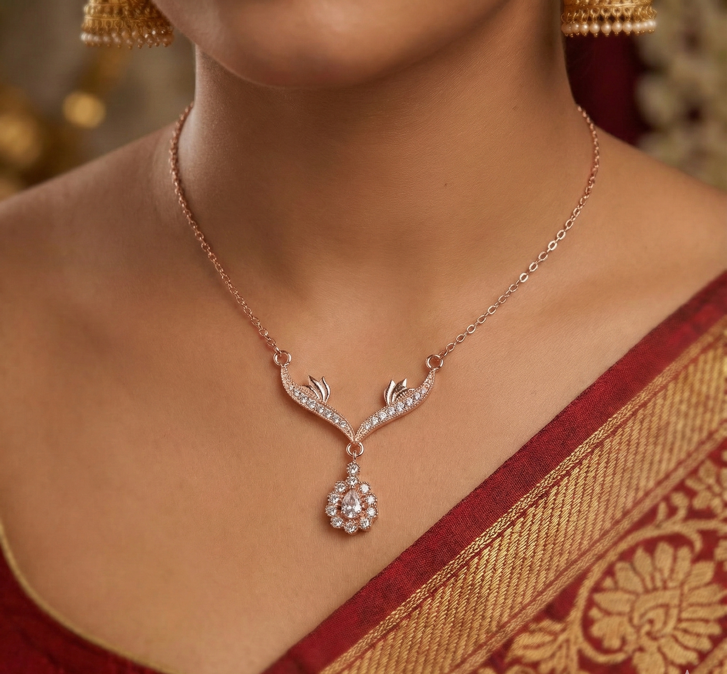 Close-up of woman wearing diamond pendant necklace with gold chain and red saree with gold border