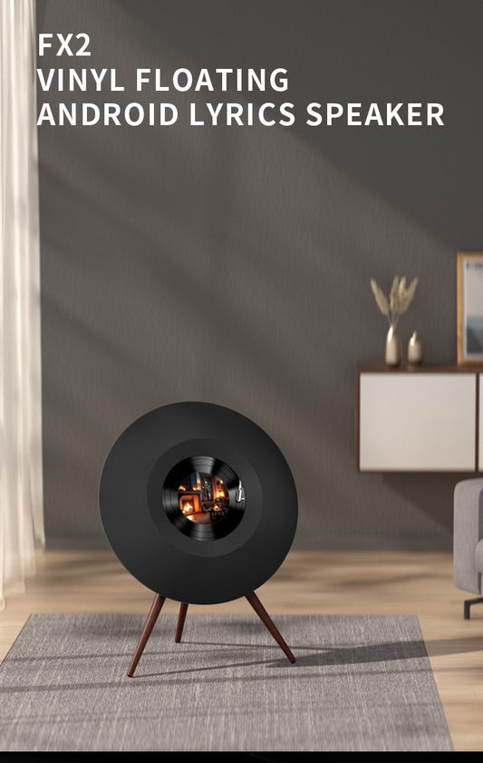 Modern black circular vinyl-style speaker on wooden tripod in stylish living room with gray rug