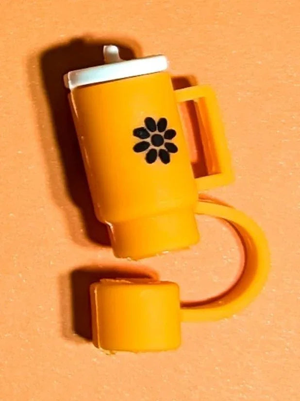 Orange plastic tumbler with handle and white lid, featuring black flower design on orange background