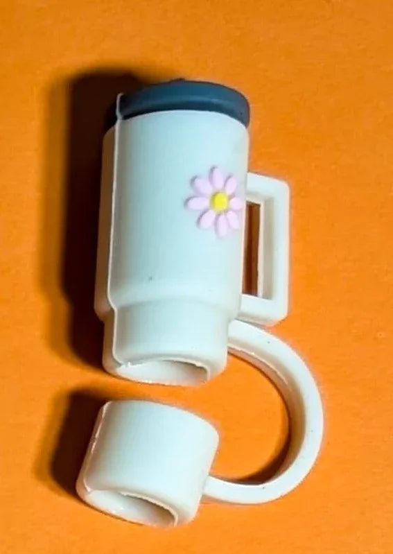 Small white tumbler with handle and pink flower detail on orange background