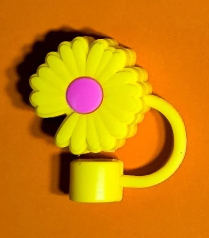 Yellow daisy-shaped keychain with pink center on orange background casting shadow