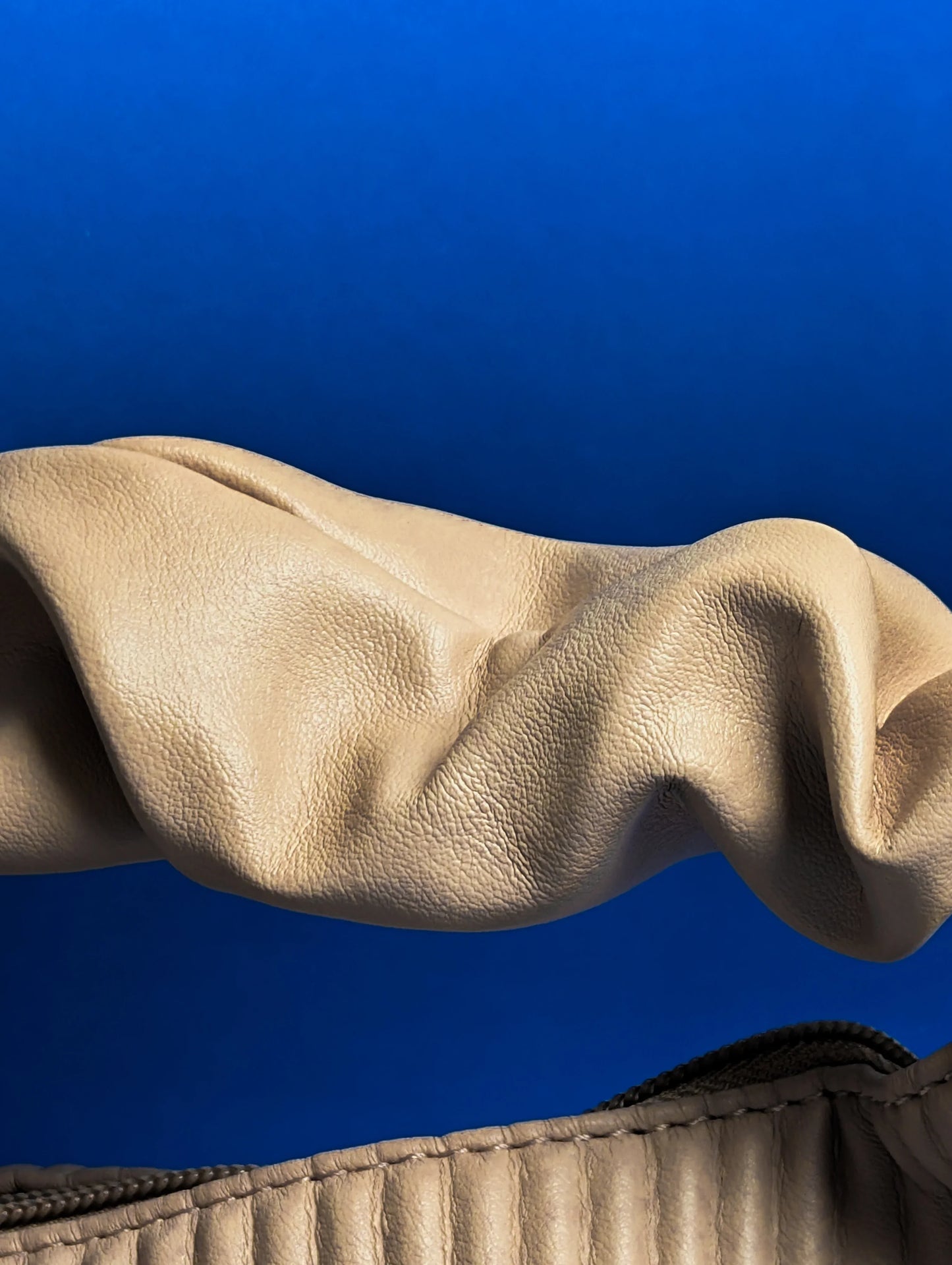 Close-up of beige leather with texture and folds against a blue background
