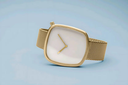 Elegant gold wristwatch with a mesh strap and square minimalist white dial on blue background