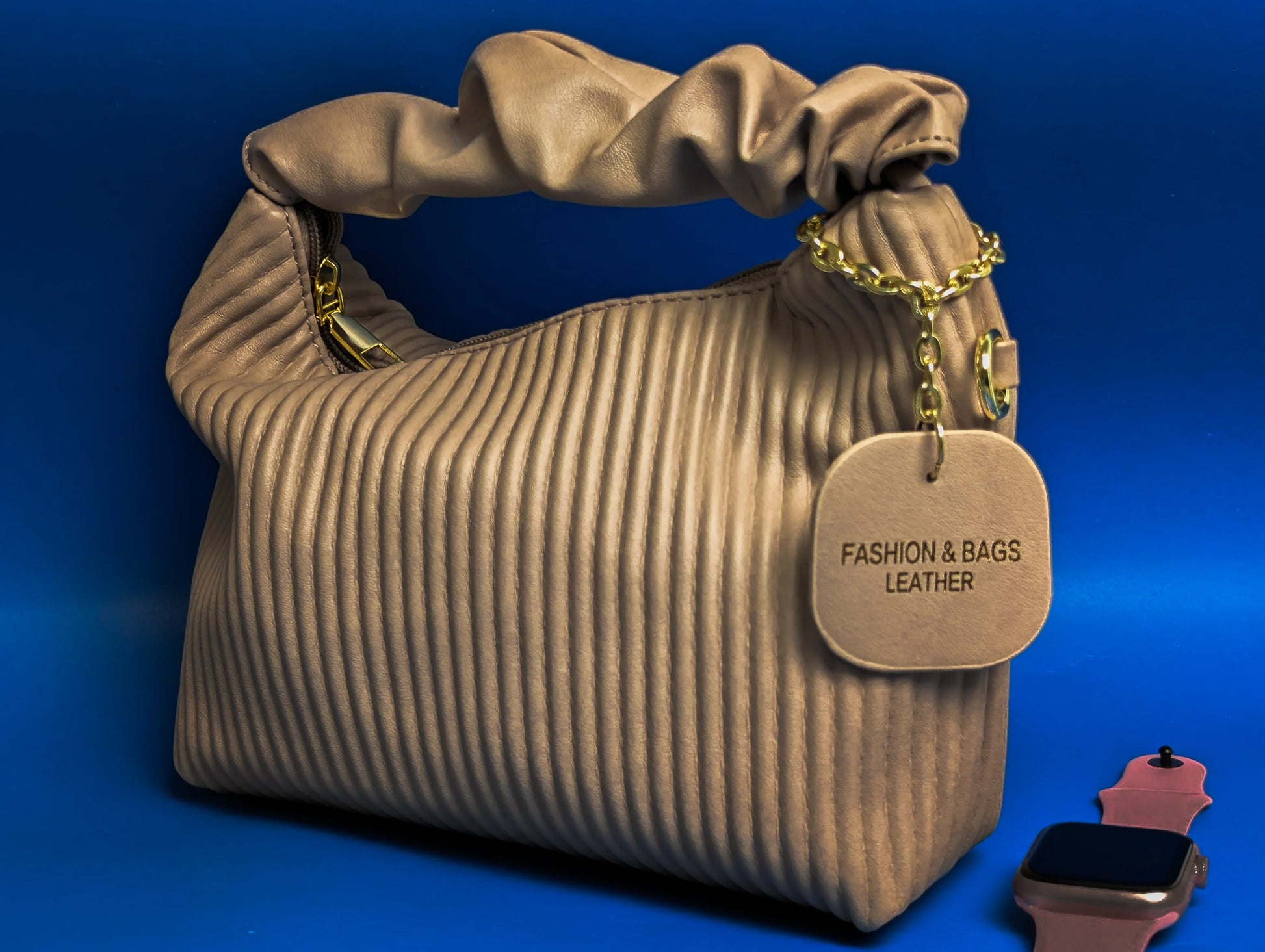 Beige leather handbag with ruched handle and gold chain tag labeled Fashion & Bags Leather on blue background
