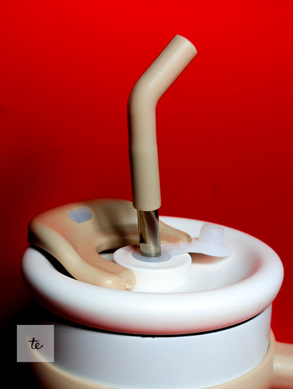 Close-up of a beige straw inserted into a white sippy cup lid against a red background