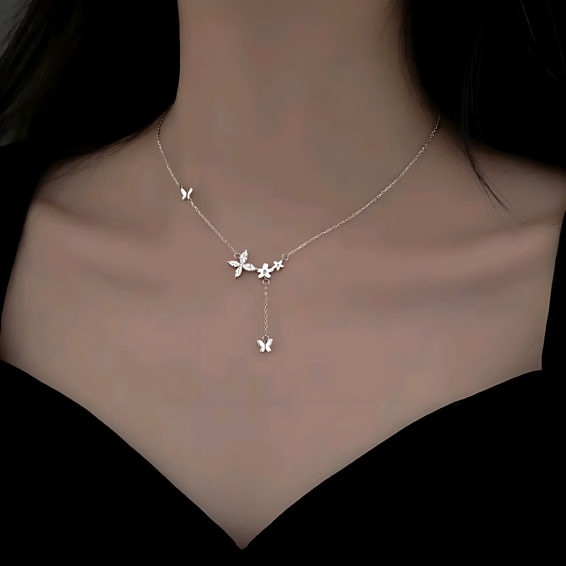 Delicate silver butterfly necklace on a woman's neck with a black off-shoulder top
