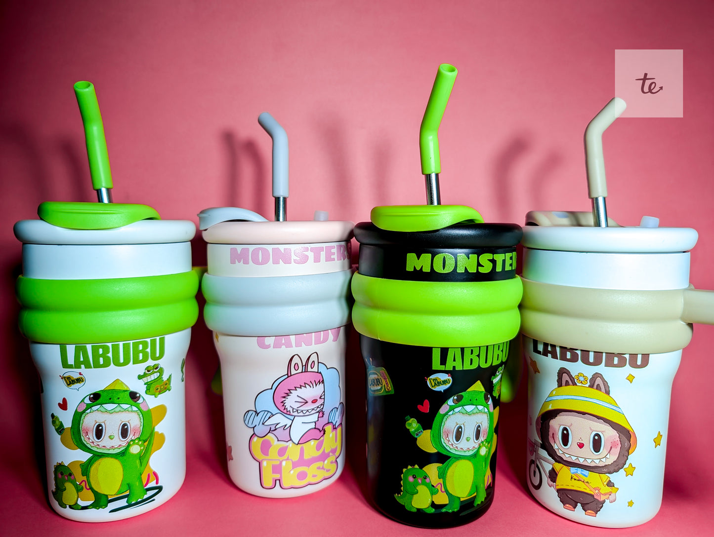 Four cute cartoon-themed sippy cups with straws on a pink background, featuring Labubu and Monster designs