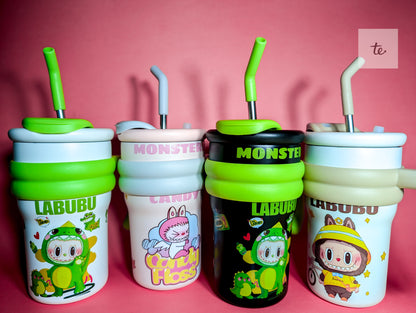 Four cute cartoon-themed sippy cups with straws on a pink background, featuring Labubu and Monster designs