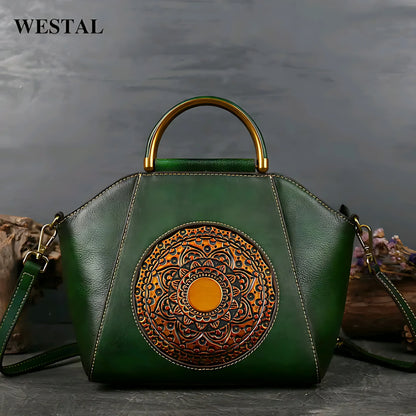 Green leather handbag with gold circular embossed mandala design and metal handle on gray surface