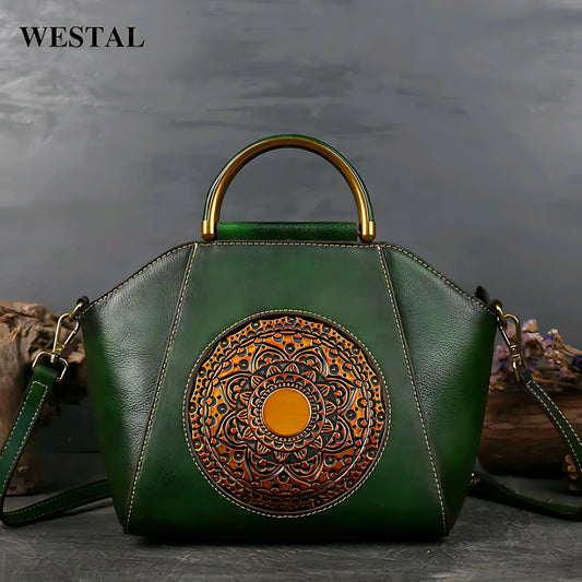 Green leather handbag with gold circular embossed mandala design and metal handle on gray surface
