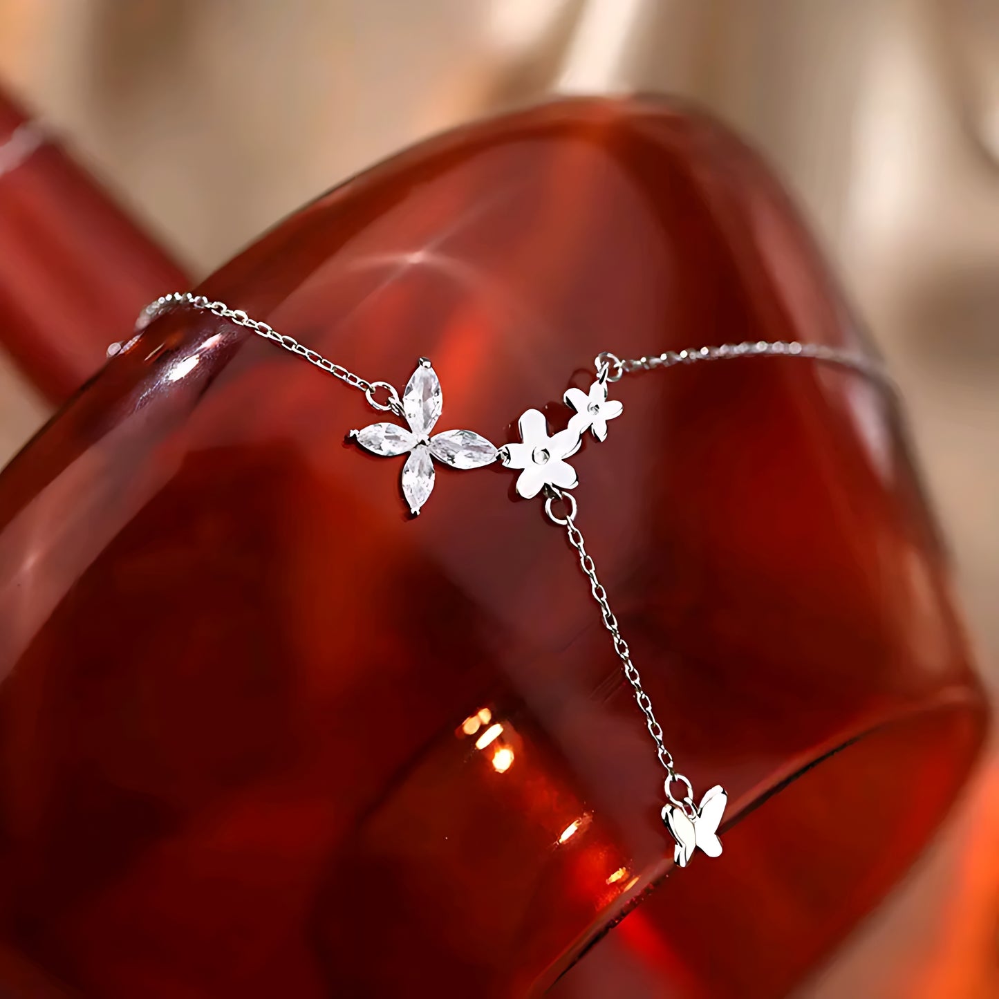 silver butterfly and flower necklace draped over a glossy amber glass surface