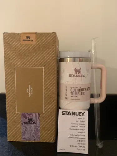 Stanley Quencher H2O Tumbler with pink handle, box, and care instructions on dark surface